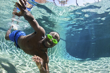 Junger Mann schwimmt unter Wasser im Pool, Porträt - ISF17246