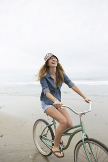 Woman riding bicycle on beach - ISF17270