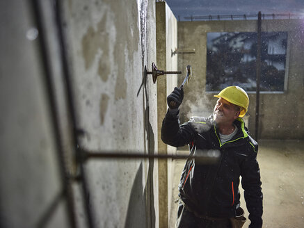 Bauarbeiter, der mit einem Hammer die Eisenstange anbringt - CVF00984