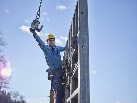 Construction worker reaching for hook of crane stock photo