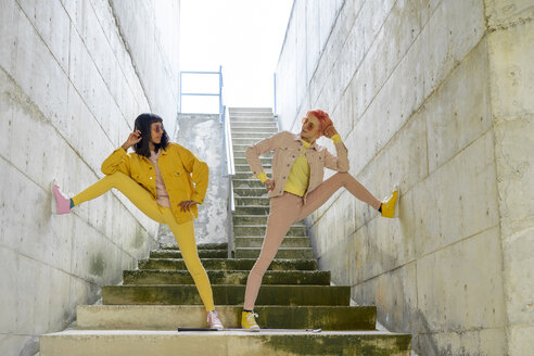 Two alternative friends posing on steps, wearing yellow and pink jeans clothes - AFVF01015