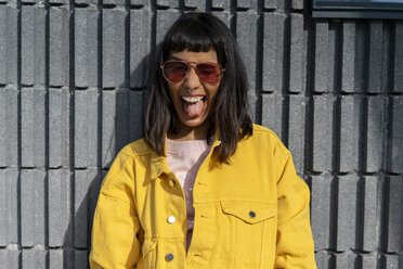 Porträt einer jungen Frau, die eine gelbe Jeansjacke trägt - AFVF01034