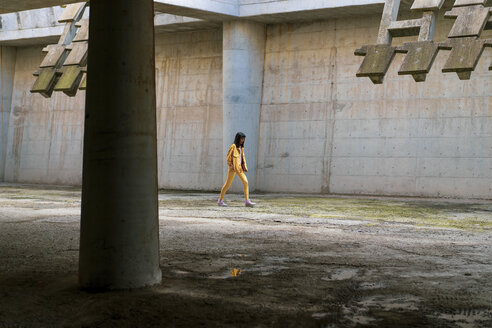 Young woman wearing yellow jeans clothes, walking - AFVF01039