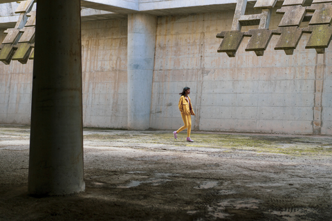 Junge Frau in gelber Jeanskleidung, zu Fuß, lizenzfreies Stockfoto