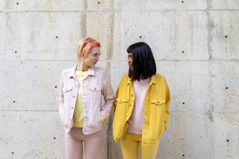 Two alternative friends having fun, wearing yellow and pink jeans clothes, face to face - AFVF01041