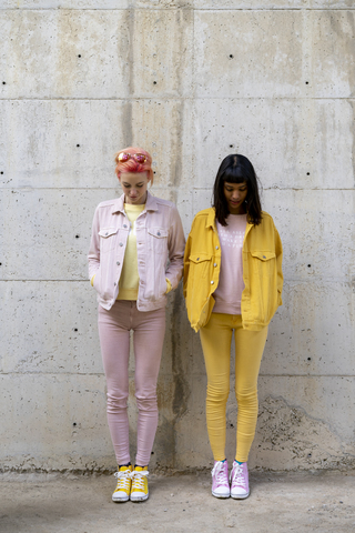 Two alternative friends having fun, wearing yellow and pink jeans clothes, looking down stock photo