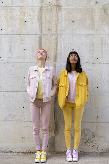 Two alternative friends having fun, wearing yellow and pink jeans clothes, looking up - AFVF01044
