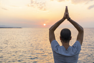 Spanien: Mann macht Yoga bei Sonnenaufgang, hebt die Arme, Rückansicht - AFVF01061