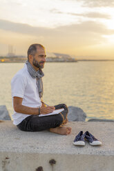 Spain. Man writing on a notebook during sunrise - AFVF01069