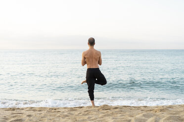 Spanien: Mann beim abendlichen Yoga am Strand, Baumstellung, Rückansicht - AFVF01073
