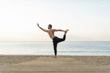 Spain. Man doing yoga on the beach in the evening, dancer position - AFVF01078