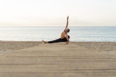 Spain. Man doing yoga on the beach in the evening - AFVF01079