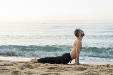 Spanien: Mann macht abends am Strand Yoga, Kobra-Pose - AFVF01084