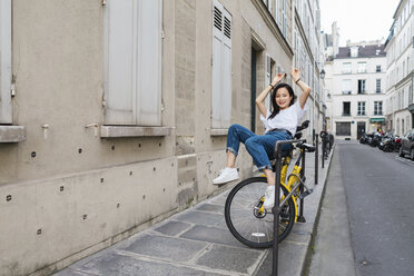 Playful young woman on bicycle at the roadside - AFVF01090