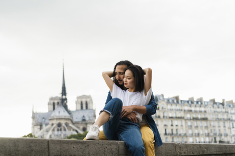 Frankreich, Paris, junges Paar sitzt auf einer Mauer am Fluss Seine, lizenzfreies Stockfoto