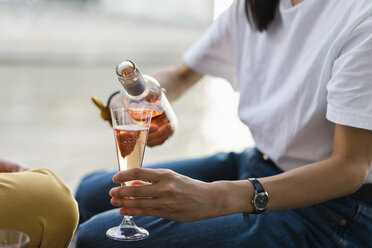 Close-up of woman pouring in sparkling blush wine - AFVF01111