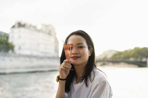 Frankreich, Paris, Porträt einer jungen Frau mit Sektglas an der Seine, lizenzfreies Stockfoto