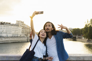 Frankreich, Paris, glückliches junges Paar, das ein Selfie am Fluss Seine bei Sonnenuntergang macht - AFVF01119