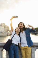 Frankreich, Paris, glückliches junges Paar, das ein Selfie am Fluss Seine bei Sonnenuntergang macht - AFVF01120