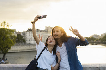 Frankreich, Paris, glückliches junges Paar, das ein Selfie am Fluss Seine bei Sonnenuntergang macht - AFVF01121