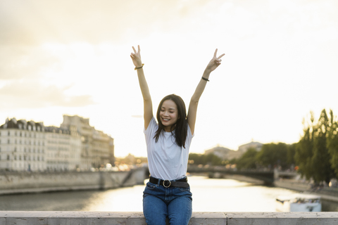 Frankreich, Paris, Porträt einer glücklichen jungen Frau am Fluss Seine bei Sonnenuntergang, lizenzfreies Stockfoto