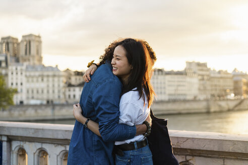 Frankreich, Paris, glückliches junges Paar, das sich am Fluss Seine bei Sonnenuntergang umarmt - AFVF01129