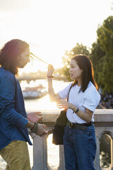 Frankreich, Paris, junges Paar steht auf einer Brücke an der Seine bei Sonnenuntergang - AFVF01130