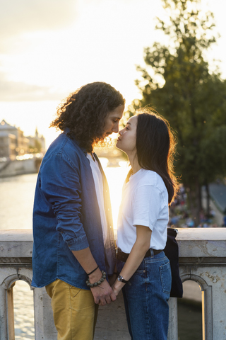 Frankreich, Paris, verliebtes junges Paar an der Seine bei Sonnenuntergang, lizenzfreies Stockfoto