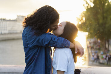 France, Paris, affectionate young couple kissing at river Seine at sunset - AFVF01137