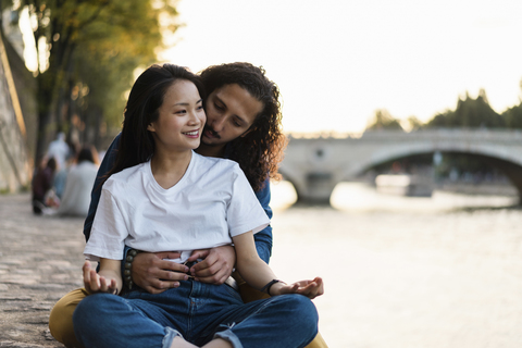 Frankreich, Paris, glückliches junges Paar am Fluss Seine bei Sonnenuntergang, lizenzfreies Stockfoto