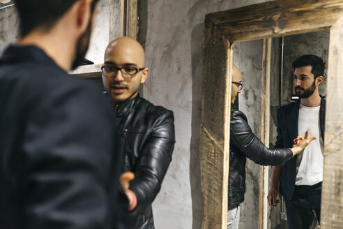 Mann spricht mit einem Kunden, der einen neuen schicken Anzug trägt, vor einem Spiegel - JRFF01705