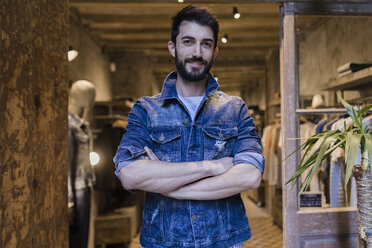 Portrait of smiling man wearing denim jacket in menswear shop - JRFF01715