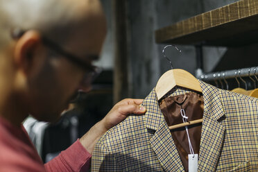 Mann betrachtet eine Jacke in einem Herrenbekleidungsgeschäft - JRFF01719