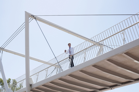 Geschäftsmann zu Fuß auf städtischer Brücke, lizenzfreies Stockfoto