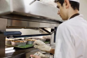 Bäcker schiebt Essen in den Ofen in der Küche - ISF17502