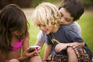 Children listening to earphones outdoors - ISF17542