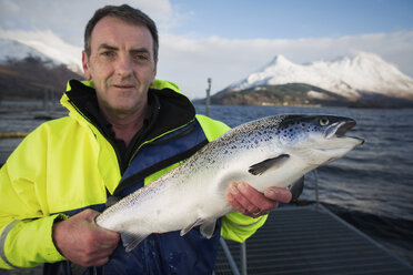 Worker holding farmed salmon - ISF17561