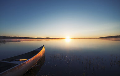 Ein Kanu auf einem flachen, ruhigen See bei Sonnenuntergang. - MINF02882