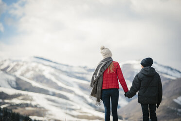 A brother and sister standing side by side in the snow, back view. - MINF02888