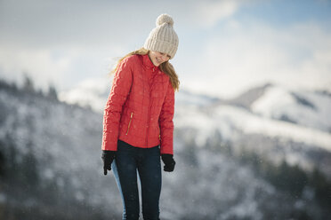 Ein junges Mädchen in einem roten Mantel und einer Wollmütze im Freien im Winter. - MINF02889