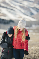 A brother and sister hugging and laughing together outdoors. - MINF02890