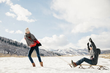Ein junges Mädchen, das seinen Bruder auf einem Schlitten durch den Schnee zieht. - MINF02896