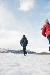 Zwei Kinder, Bruder und Schwester, rennen durch den Schnee. - MINF02899