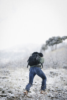 Ein Mann, der mit einem Rucksack einen Hang in den Bergen hinaufläuft. - MINF02905