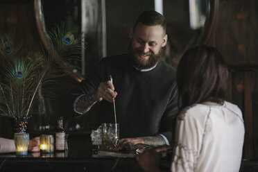 A woman and a bartender talking, and mixing drinks. - MINF02916