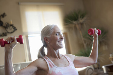 Older woman lifting weights at home stock photo