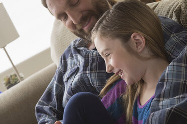 Father and daughter smiling on couch - ISF17736