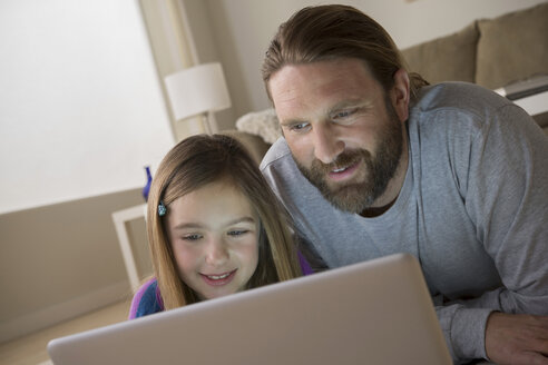 Vater und Tochter schauen auf den Laptop - ISF17763