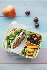 Gesundes Schulessen in der Lunchbox, vegetarisches Sandwich mit Käse, Salat, Gurke, Ei und Kresse, Karotten- und Selleriescheiben, Kirschen und Birne - IPF00466