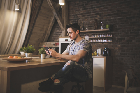 Junger Mann benutzt Tablet in der Küche zu Hause, lizenzfreies Stockfoto